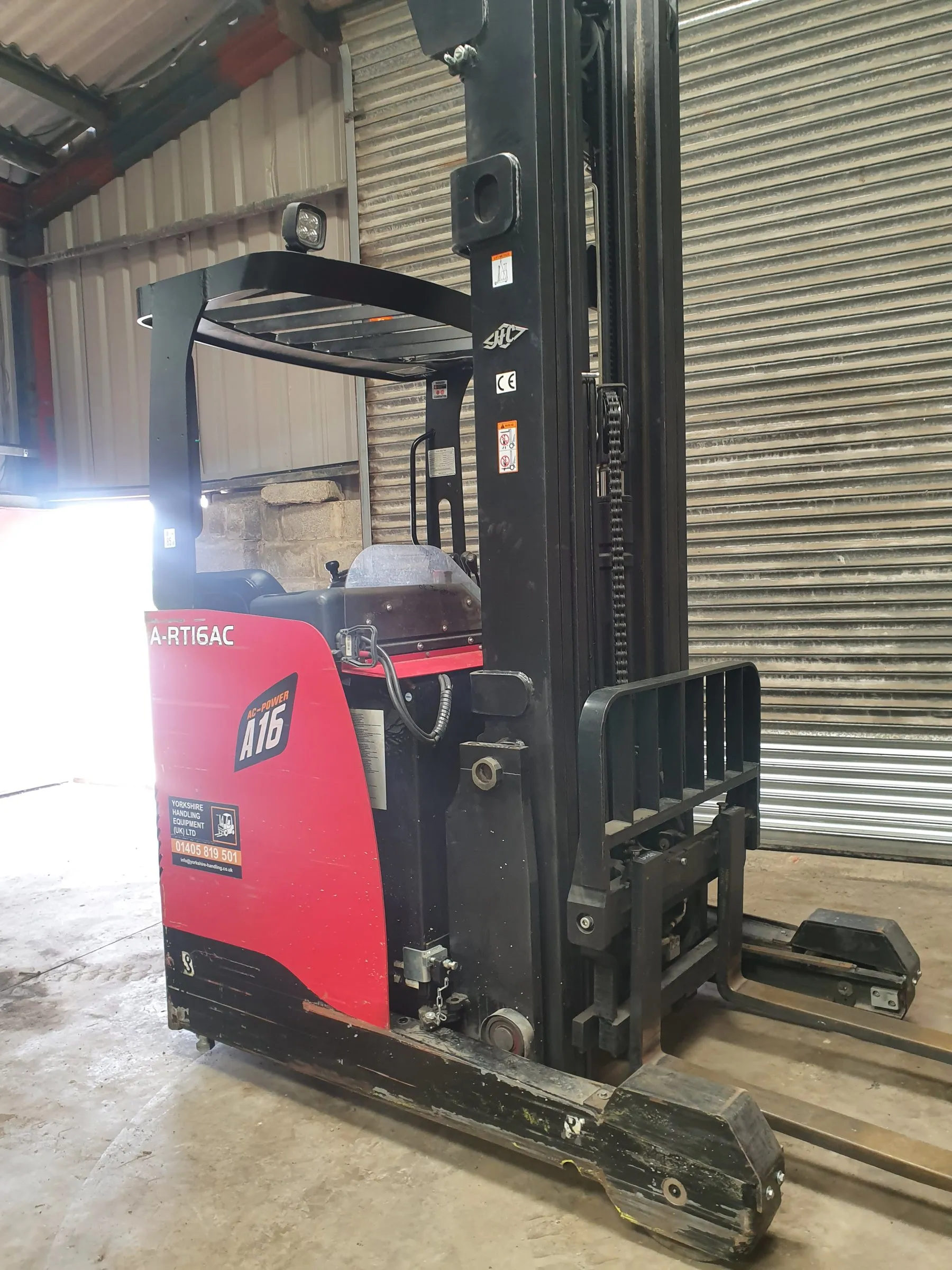 Red reach truck with its mast lowered in the workshop